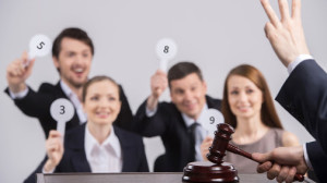 four people raising cards with number. judge counting and holding hammer in hands